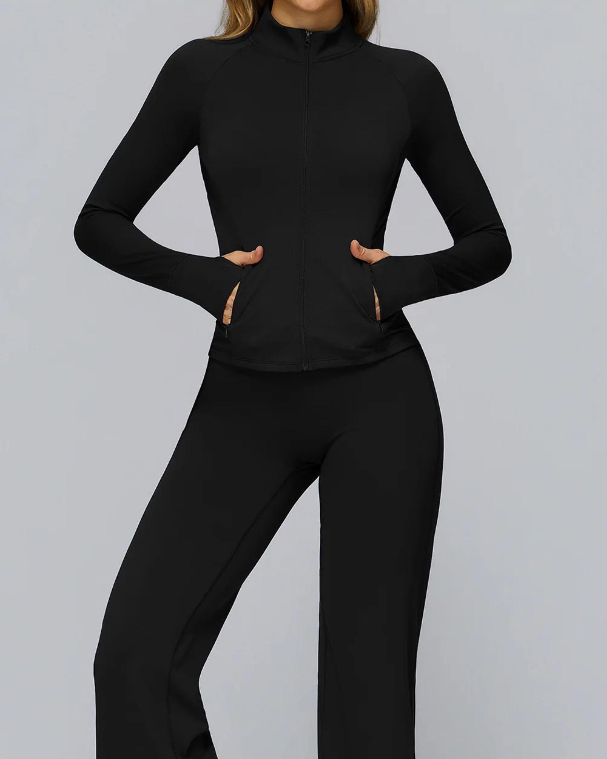 Schwarze Slim-Fit Sportjacke für Damen, durchgehender Reißverschluss, Stehkragen, Vorderansicht mit Händen in den Seitentaschen, figurformender Schnitt - Ryze.